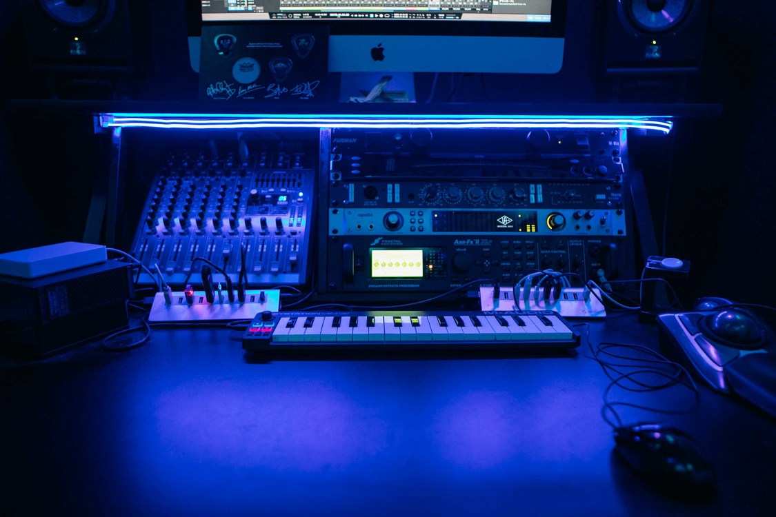 デスク上のラックには、FURMAN M-8Lx（パワー・コンディショナー）、KORG DTR-1000（チューナー）、AMS Neve 1073SPX（マイクプリアンプ／EQモジュール）、Universal Audio Apollo FireWire（オーディオインターフェース）、Fractal Audio Systems Axe-Fx II XL +（アンプシミュレーター）