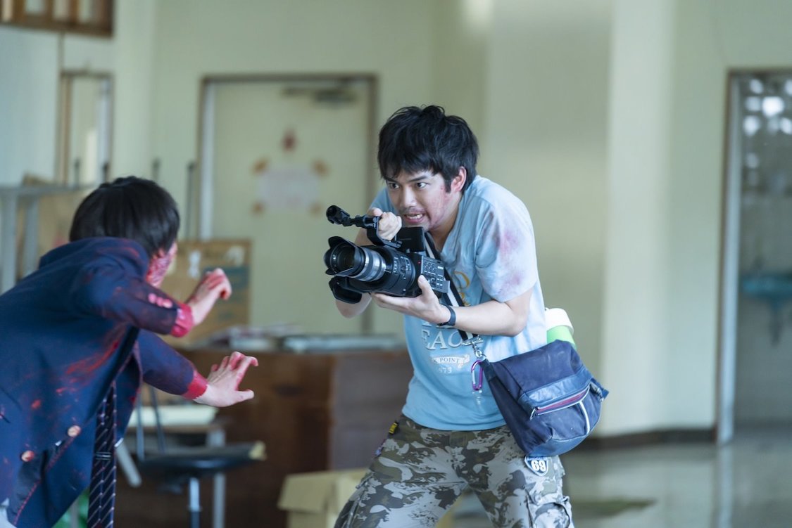 “壁ドン”映画の撮影現場で殴る蹴るのパワハラに耐えながら奮闘する【助監督】黒沢明（三浦貴大）が必死にカメラを回している。カメラを向けているのは呪われた脚本『ゴーストマスター』によってモンスター化し、血に染まった【主演俳優】桜庭勇也（板垣瑞生）。